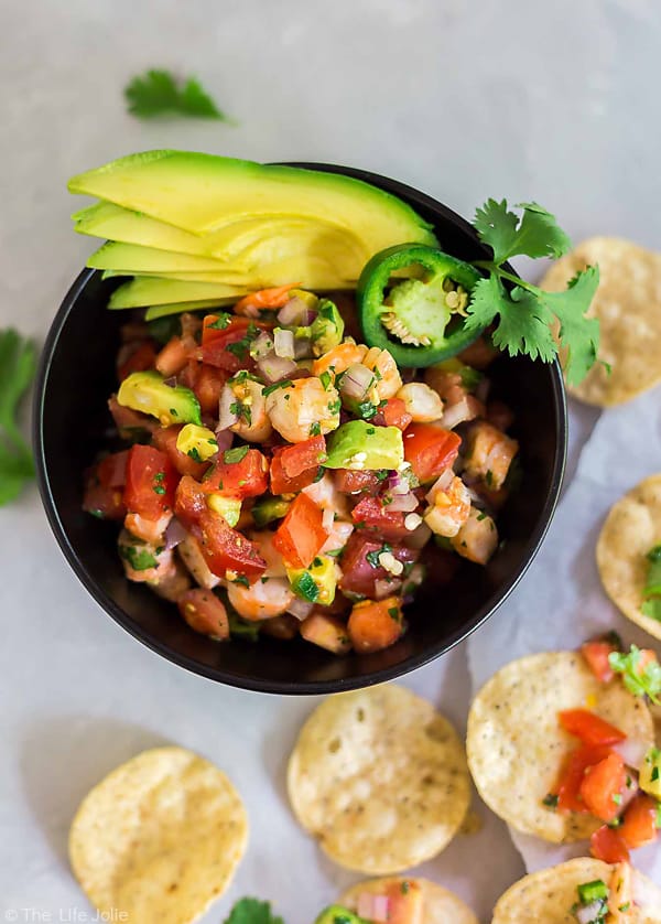 An overhead shot of 10 Minute Shrimp Salsa in a bowl with avocado and chips around the bottom of it.
