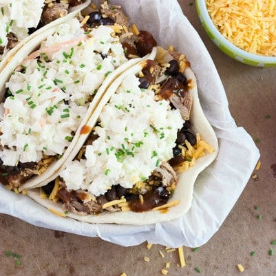 This BBQ Pulled Pork Tacos recipe is a fun twist on traditional mexican tacos. The pulled pork is super easy to make in the crockpot or a great way to use pulled pork leftovers. I make this with slaw and a bunch of other tasty ingredients. Click on the photo to get the recipe!