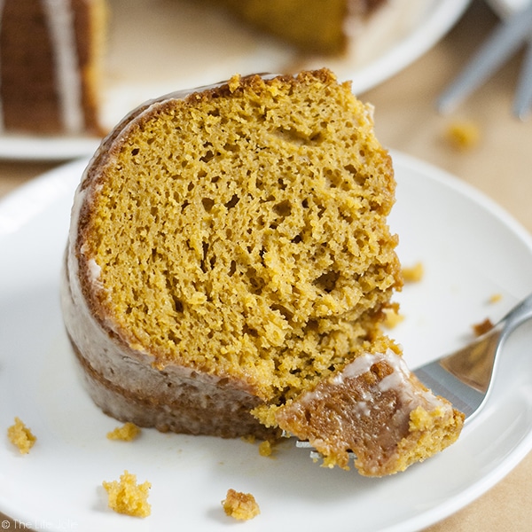 An image of a slice of pumpkin cake with a fork in front of it holding a bite of the cake on it.