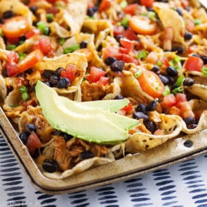 These Sheet Pan Chicken Nachos are an easy and delicious game day snack recipe! They are so simple to put together and bake up in the oven with tortilla chips, leftover taco meat, plenty of cheese and all sorts of other great toppings! You've got to try these!