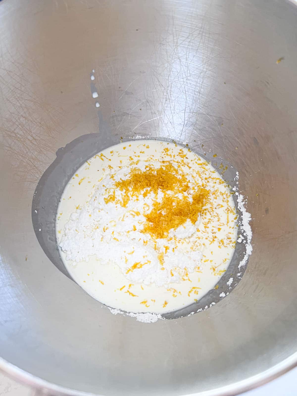Whipped cream ingredients in the metal stand mixer bowl.