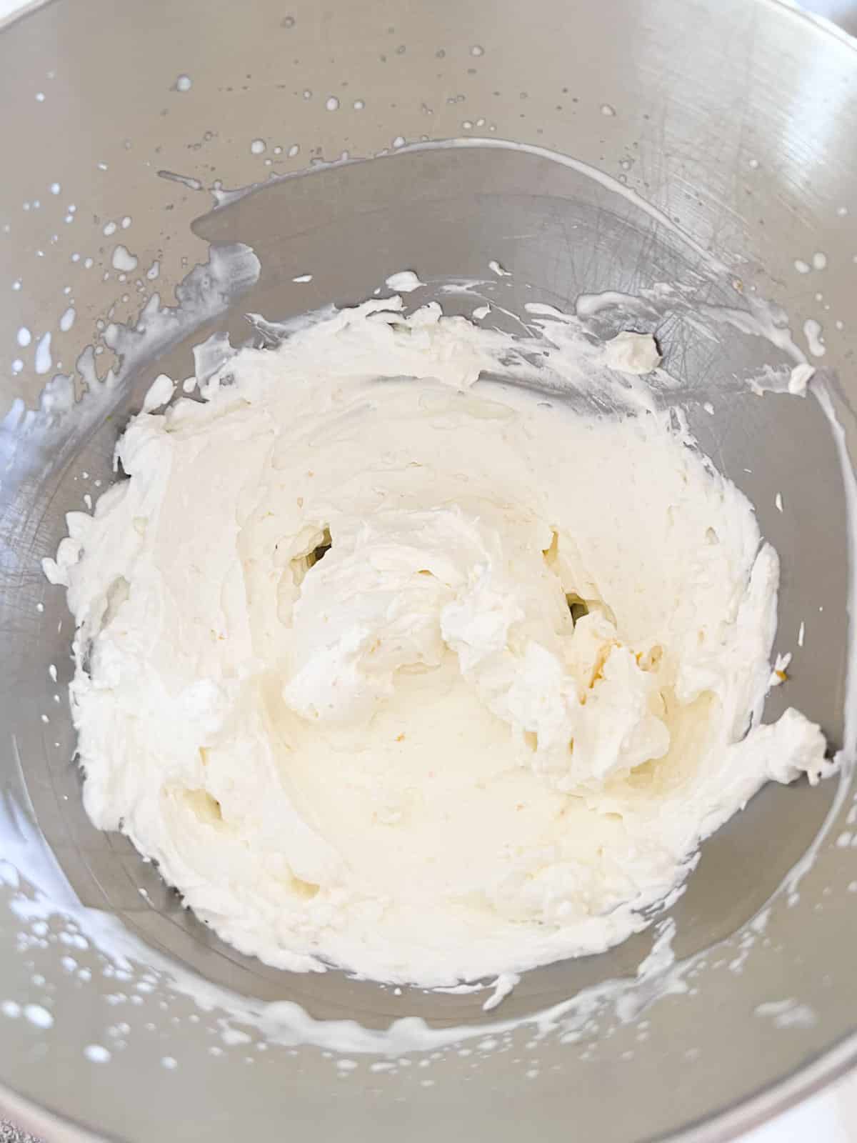 Freshly whipped cream in the metal stand mixer bowl.
