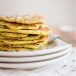 What to do with that bumper crop of zucchini? Zucchini Pancakes! Made with Bisquick, Romano cheese, shredded zucchini, butter, garlic powder and onion, they are a super easy savory breakfast and are also a great make-ahead appetizer for a party!