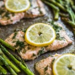 A square photo of Lemon Dill Salmon lined up on the diagonal surrounded by other pieces of salmon which are out of focus and asparagus which is also out of focus.