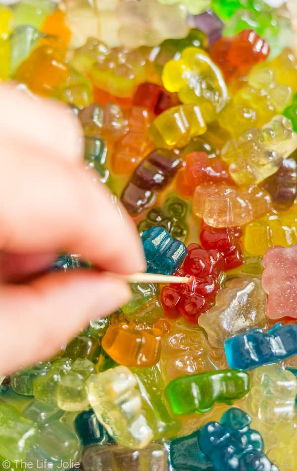 An image of a hand with a toothpick stabbing into a boozy gummy bear.