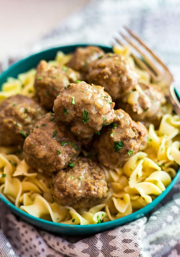 A close up image of a blue bowl of Classic Swedish Meatballs with a fork in it.