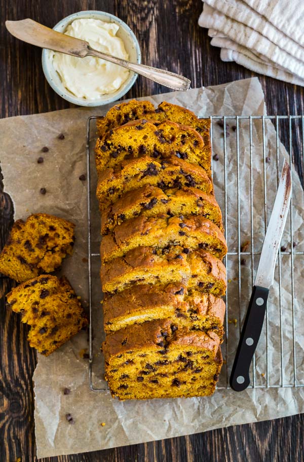 An overhead shot of pieces of Pumpkin Chocolate Chip Bread spread out on a cooling rack with a knife and pieces of the bread around it.