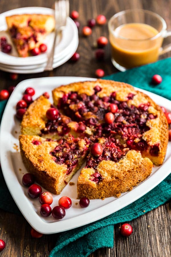 Orange Cranberry Torte cut into pieces on a white plate with cranberries around it.