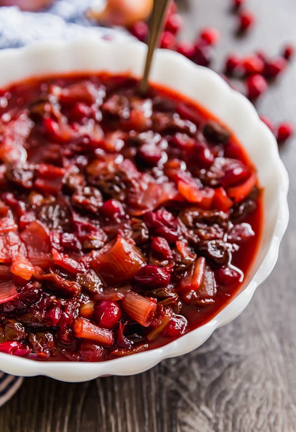 A close up of a bowl of Homemade Cranberry Sauce with Dried Cherries and Shallots with half of it cut off.