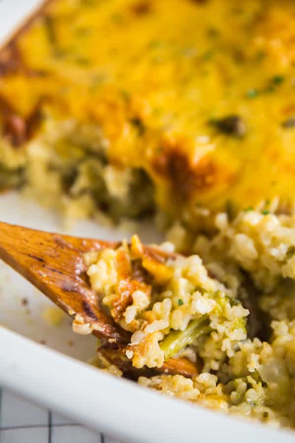 A pan of Cheesy Broccoli Rice Casserole with a wooden serving spoon in it.