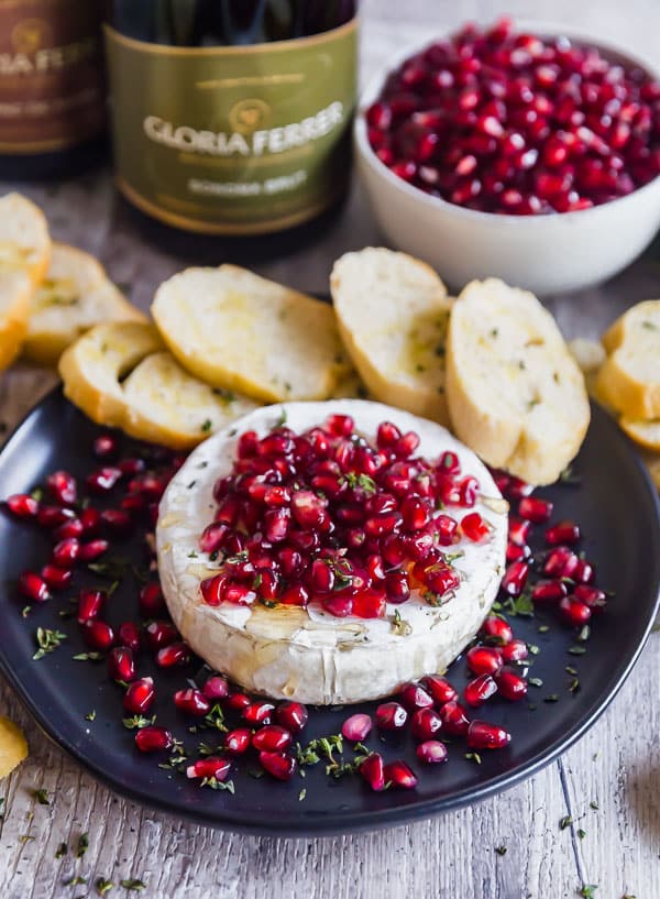 Pomegranate and Thyme Baked Brie Appetizer with sliced baguette around it.
