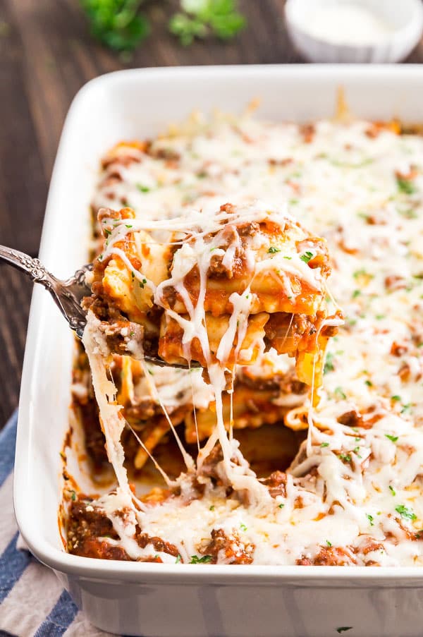 Baked Ravioli Casserole Being lifted out of a pan.