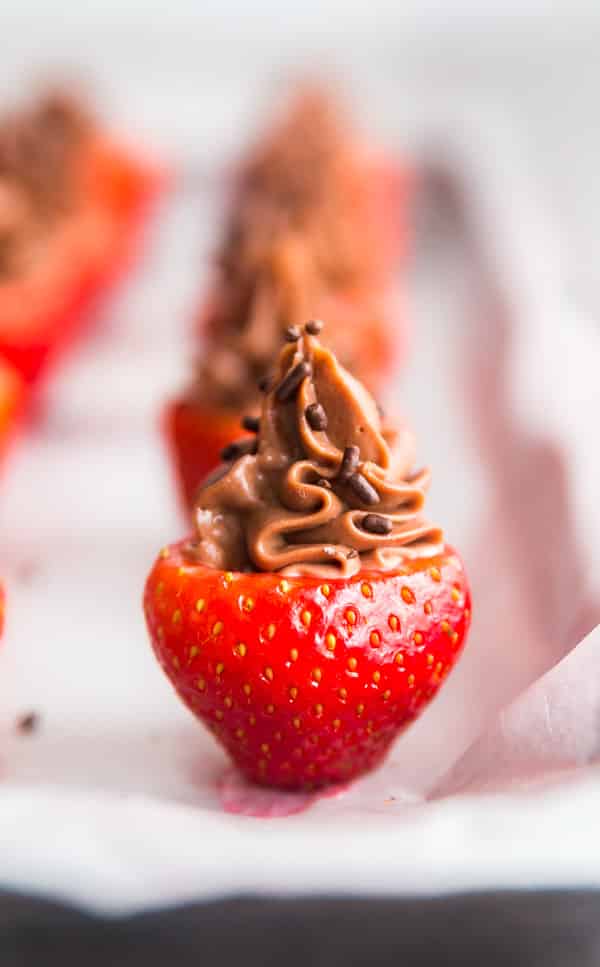 A Chocolate Cheesecake Stuffed Strawberry on a pan wih others out of focus in the background.