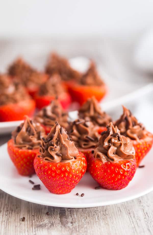 Chocolate Cheesecake Stuffed Strawberries on a plate iwth another plate of them behind it.