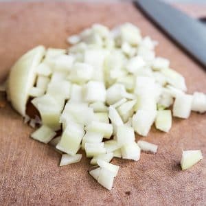 A square image of chopped onion on a cutting board.