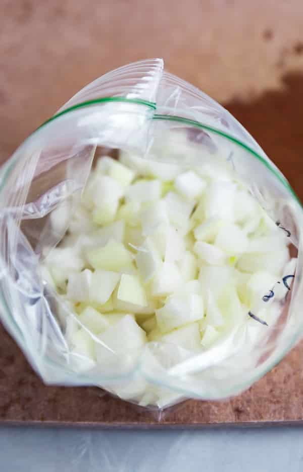 An open bag of onions on a cutting board.