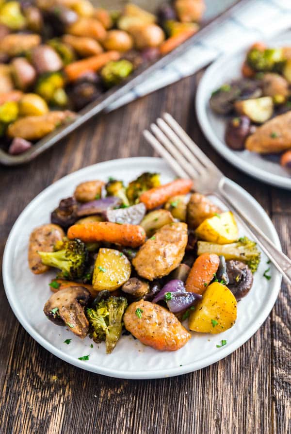 One Pan Baked Italian Sausage and Veggies on a plate with a fork on it and the pan behind it.