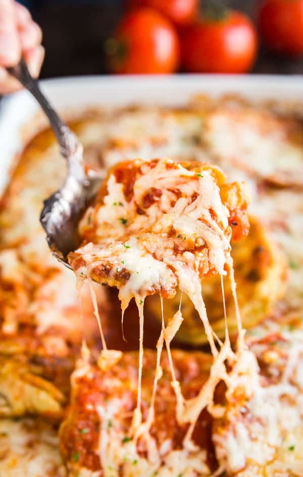 Baked Eggplant Parmesan being pulled out of a pant with stretchy cheese.