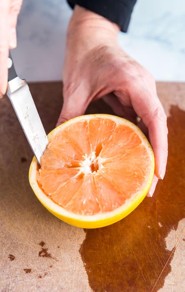 Cutting around the perimeter of the grapefruit.