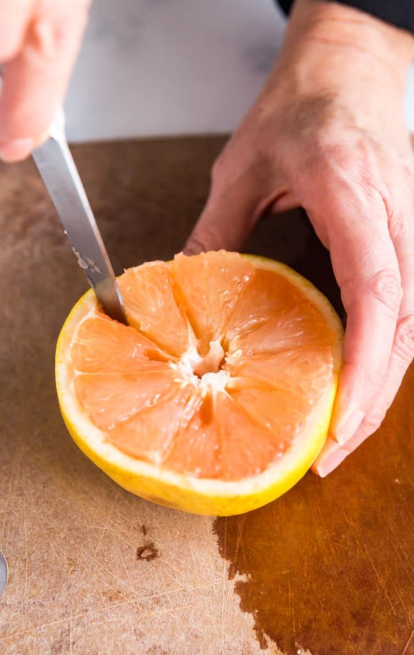 A knife cutting in to a grapefruit in this tutorial of how to cut grapefruit.
