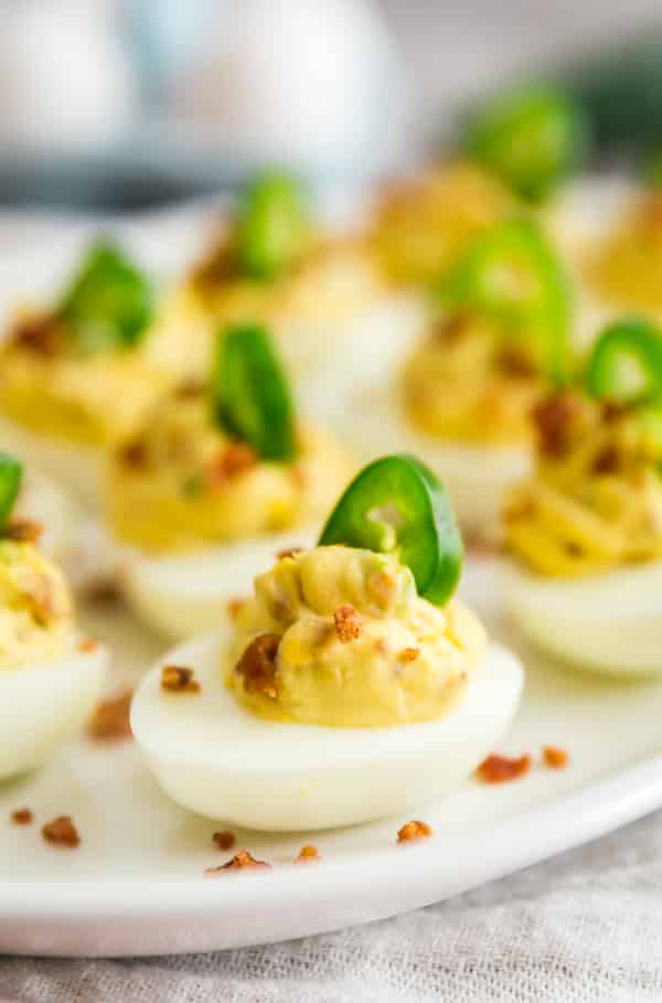 Deviled Eggs with Bacon and Jalapeños are basically Jalapeno Popper Deviled Eggs. They're cheesy, creamy and have a deliciously spicy kick! Made with eggs, bacon, cream cheese and jalapenos- these are a seriously delicious and easy appetizer for any party!
