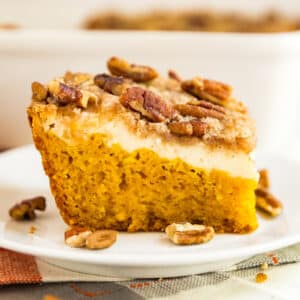 Cream Cheese Pumpkin Crunch Cake is the seriously easy fall dessert that you'll want to bring to every party! This cake mix hack includes a pumpkin sheet cake, cheesecake layer and a crumbly streusel topping with pecans. Every single person who tries it goes crazy over it and begs for the recipe.