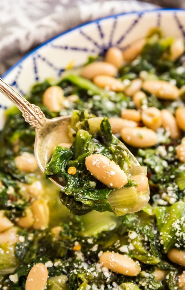 A close up of a spoonful of this greens and beans recipe with the bowl in the background.