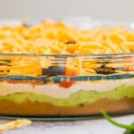 It's not a party without this classic 7 layer dip- it's one of those epic appetizers that people can't stop eating! Made with beans, guacamole, cheese, tomatoes and olives- you've got to make this for you next party!