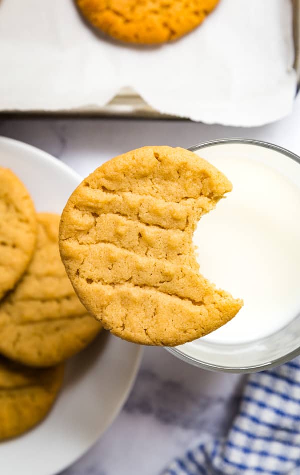 easy peanut butter cookies with one on top of a glass with a bite in it