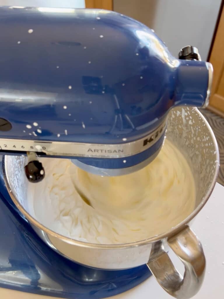 Heavy cream being whipped in a stand mixer.