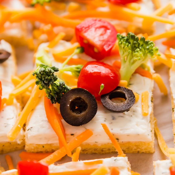 A square close up image of a piece veggie pizza surrounded by other pieces.