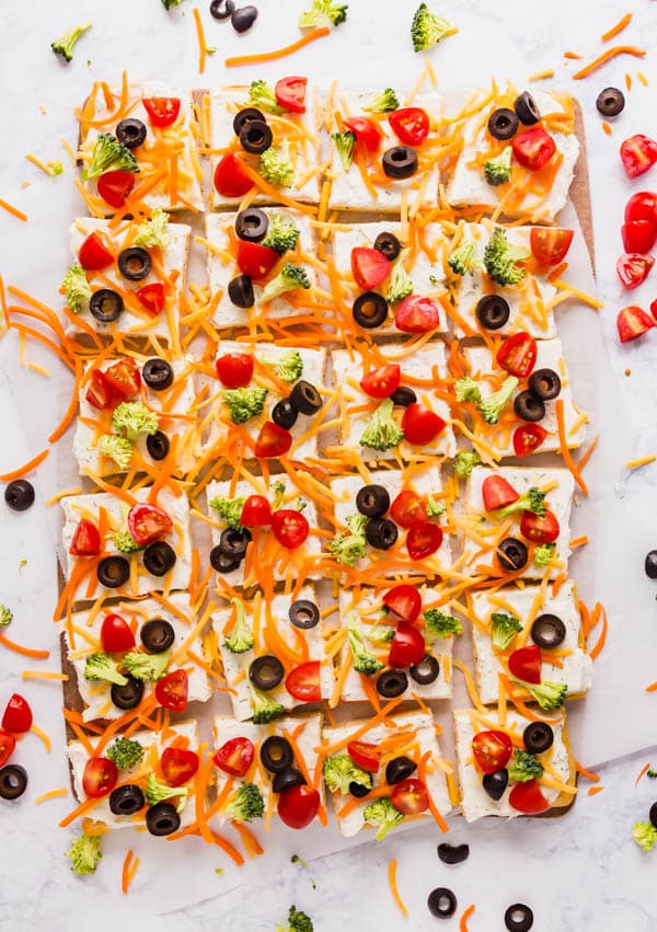 An image of crescent roll pizza pieces lined up with vegetables around them.