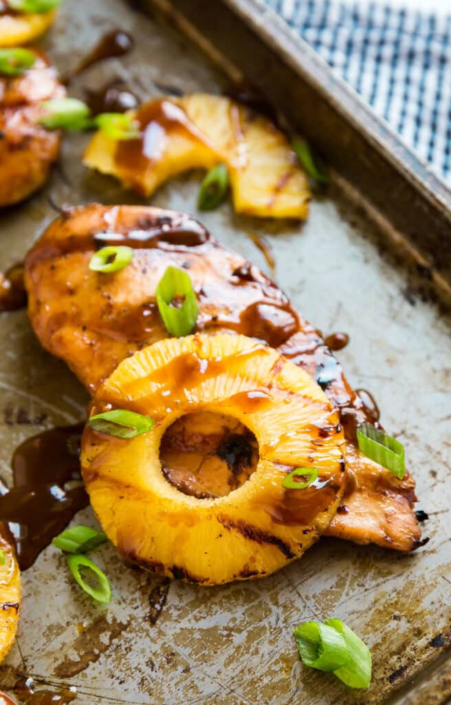 Grilled Hawaiian Chicken on a pan with pineapple and a drizzle of sauce.