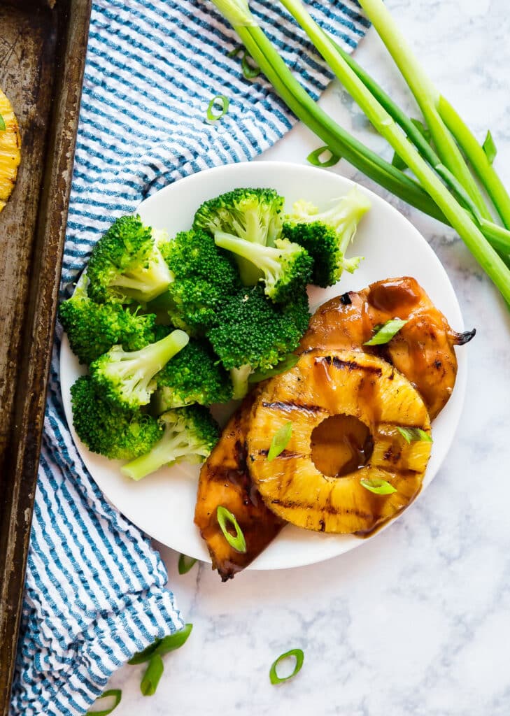 An overhead image of Hawaiian chicken on a plate with broccoli.