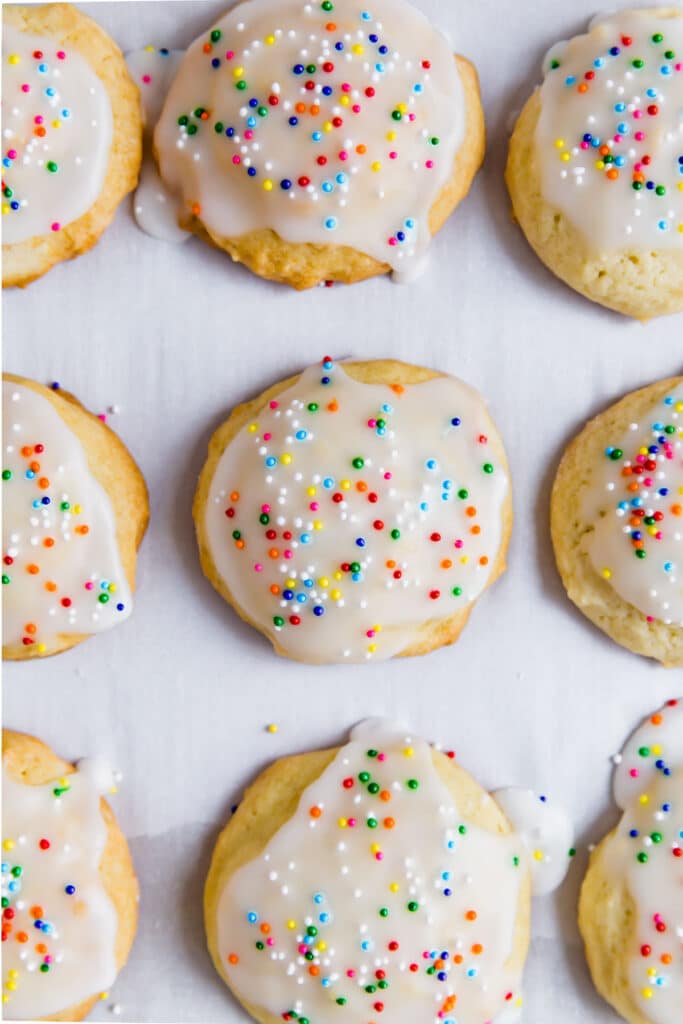 An overhead image of glazed and sprinkles cookies lined up on parchment paper.