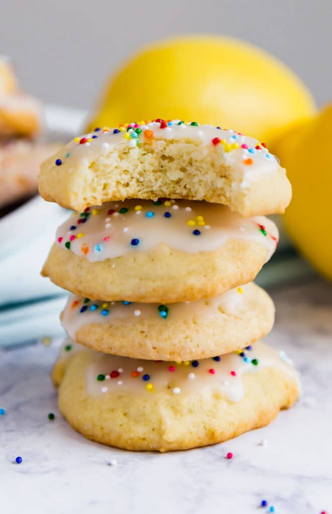 A stack of sour cream sugar cookies where the top cookie has a bite out of it.