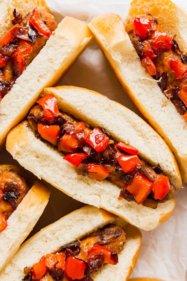 An Italian sausage sandwich with caramelized onions and peppers on it.