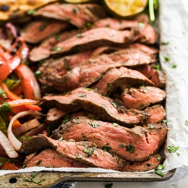 Steak Fajitas are good, but Grilled Steak Fajitas are better! Tender flank steak makes a great fajita protein with charred peppers and onions- this is an easy dinner that's perfect for a summer get-together.