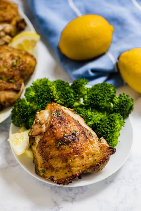 A piece of grilled chicken on a plate with broccoli and chicken behind it.