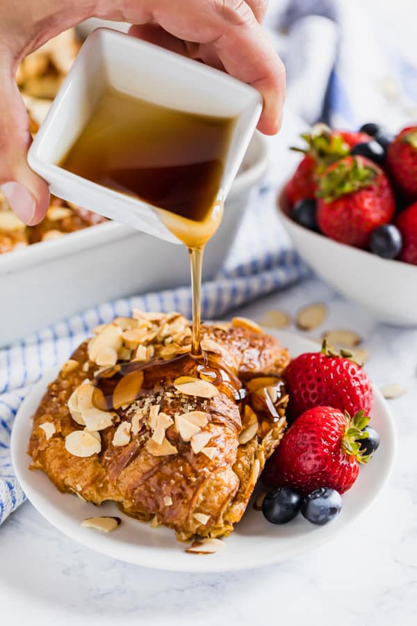 Croissant French Toast Bake on a plate being drizzled with maple syrup.