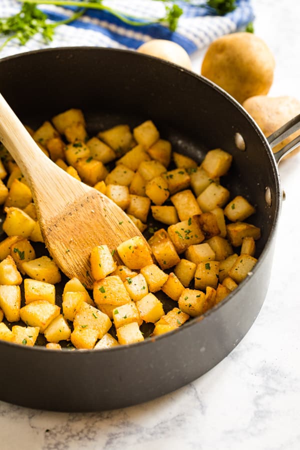 A side image of a pan of skillet potatoes with a spoon in it.