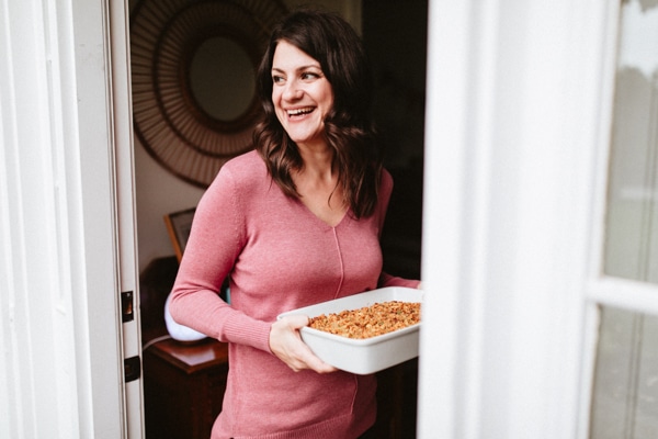 A woman in a doorway with a thanksgiving dish to pass