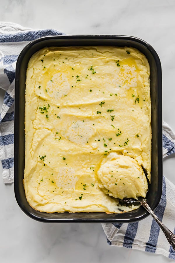 An overhead image of a pan of mashed potatoes with a spoon in it.