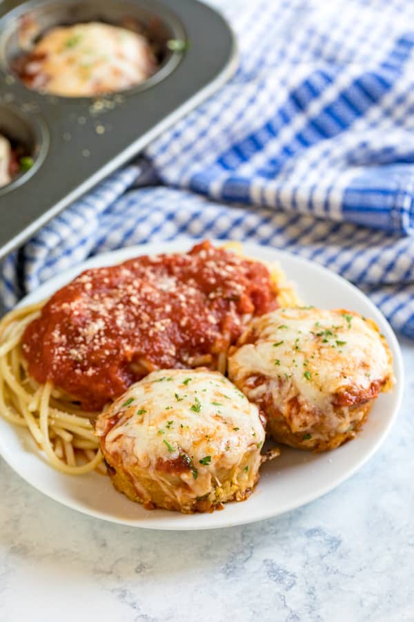 A plate of chicken parm meatloaf muffins and spaghetti on it.
