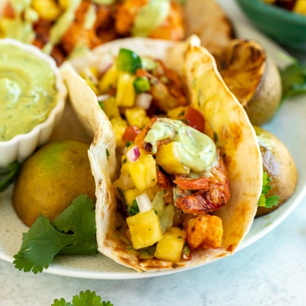 These easy Grilled Shrimp Tacos are about to be your new favorite summertime dinner recipe! Topped with pineapple salsa and an avocado cream sauce, they're quick and easy to make with flavor that will keep you coming back for more.