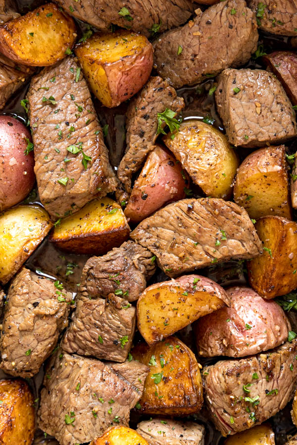 An overhead image zooming in on steak and potatoes in the pan.