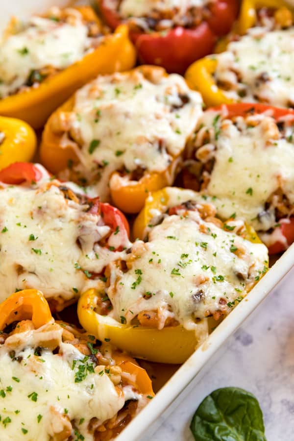 Stuffed peppers lined up in a pan from a side angle.