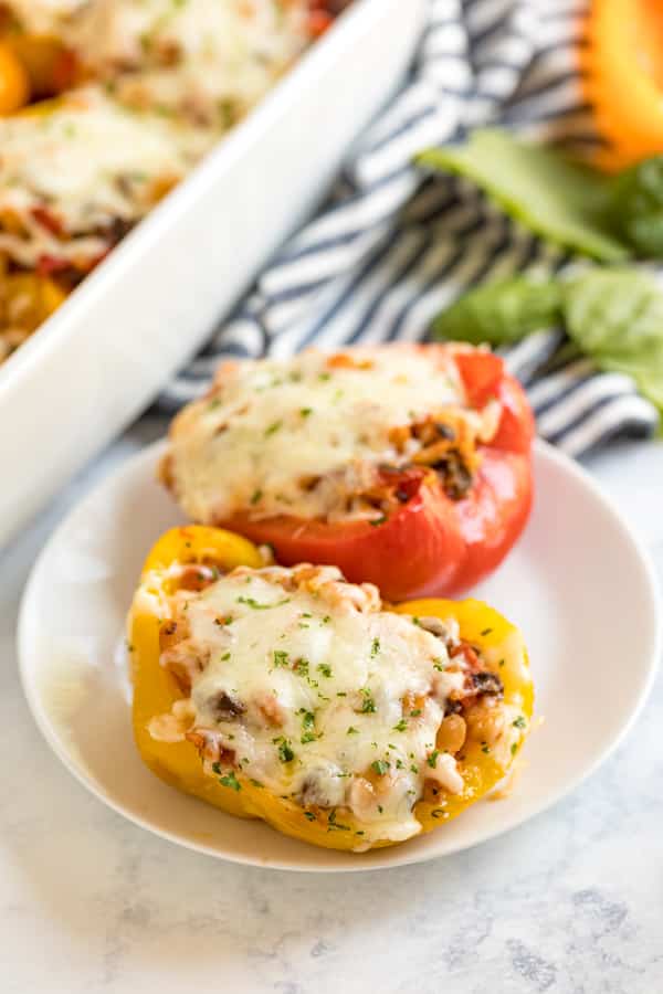 Two stuffed peppers on plates.