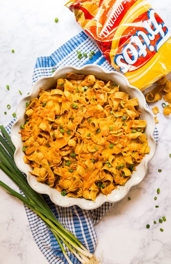 An overhead image of a finished Frito Taco Casserole recipe with Fritos and scallions on the side of it.