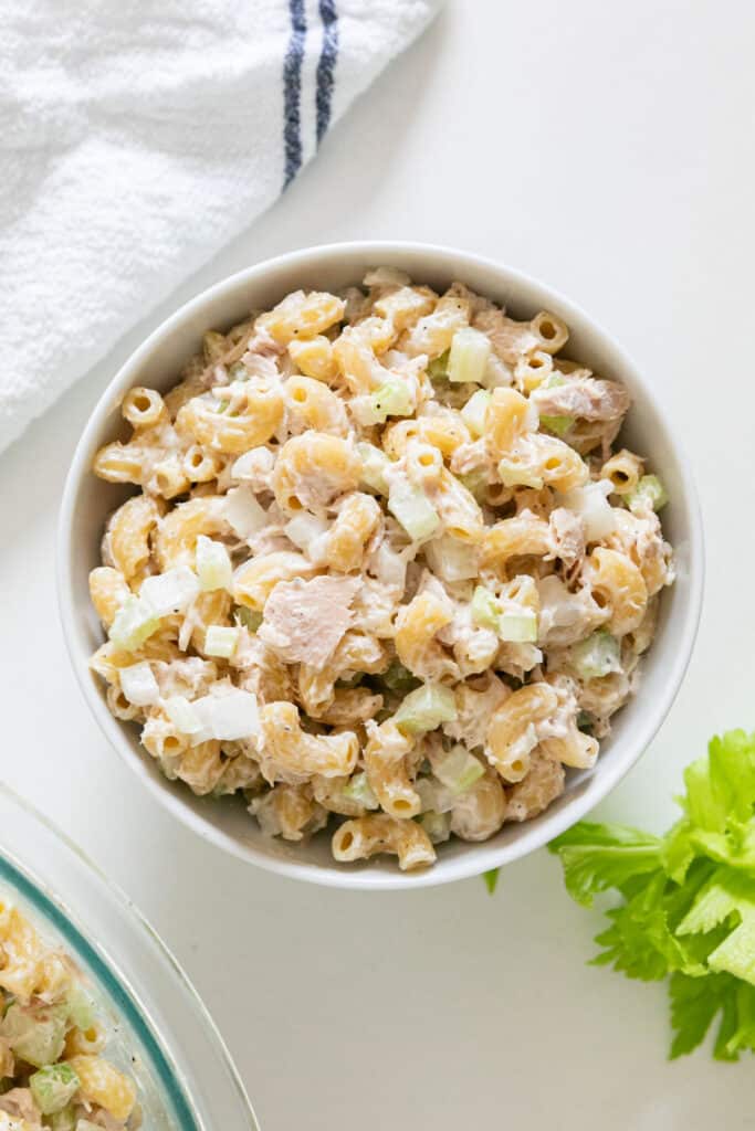 An over head image of macaroni salad with tuna in white bowl.